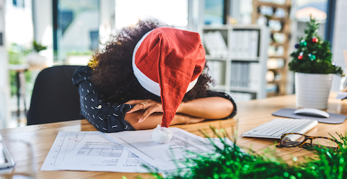 woman wearing Santa Claus hat with head on desk