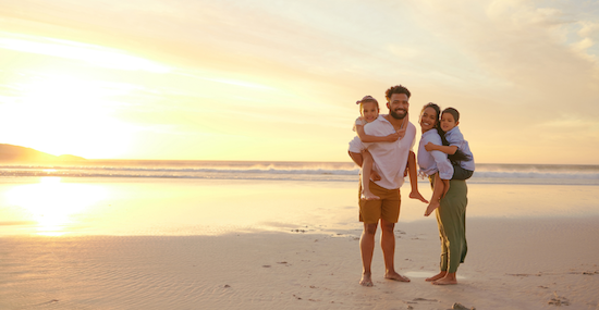 Family of four poses on beach